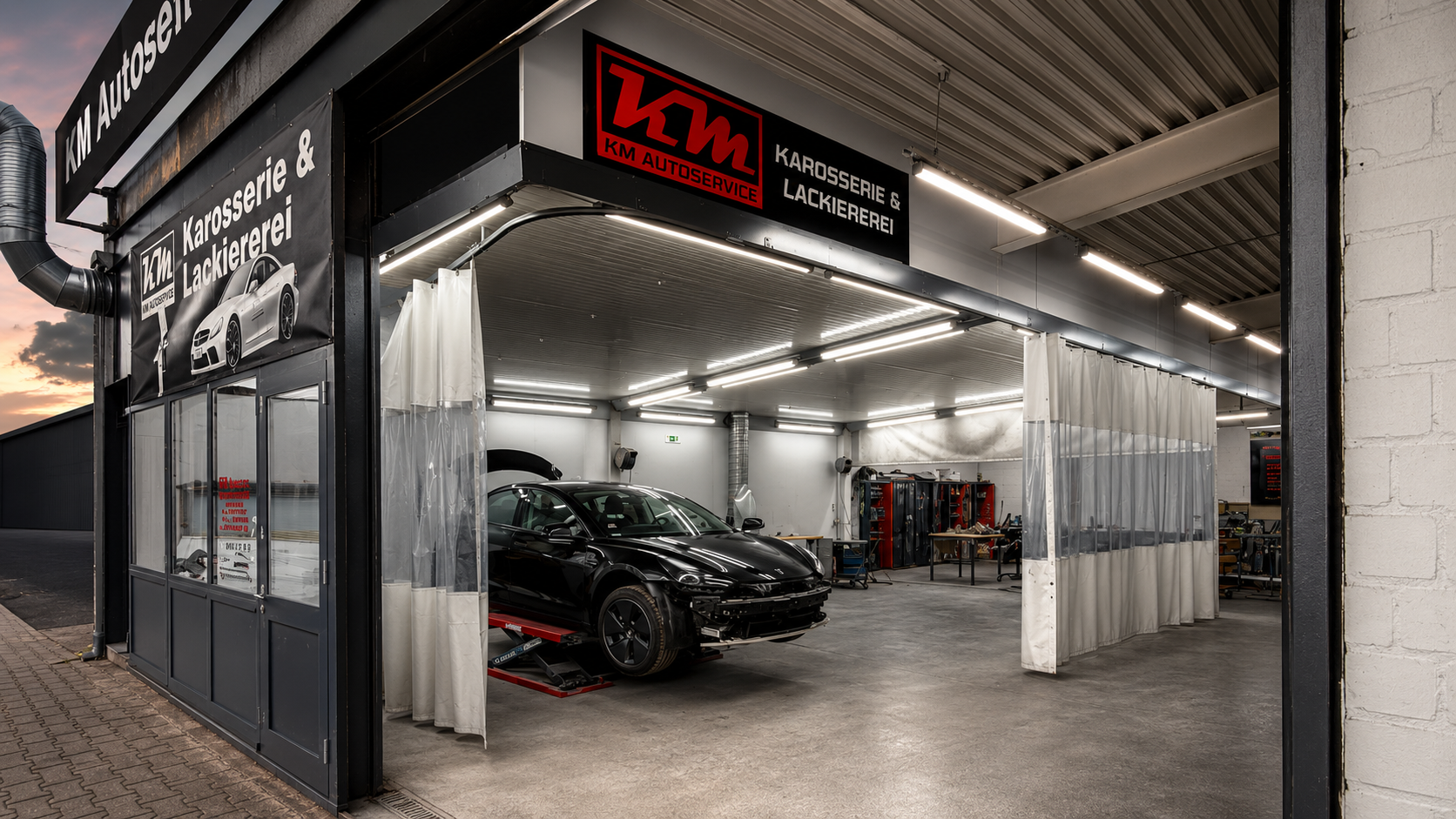 Eingang der KM Autoservice Werkstatt bei Sonnenuntergang